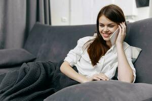 happy woman talking on the phone on the sofa indoors photo