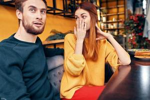 handsome man and happy woman in sweater are sitting at a table in a cafe chatting room interior photo