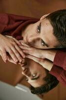 man in shirt lay down on glass and reflection portrait brown background photo