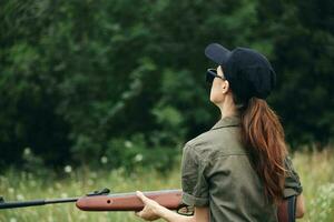 Woman soldier with a gun in his hands dark glasses back view fresh air photo