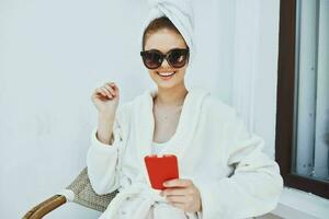 cheerful woman in a white robe, dark glasses, use the phone photo