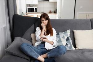 sad woman with phone in hand at home apartment communication photo