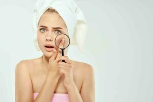 woman with bare shoulders with towels talking skin problems magnifier near face photo