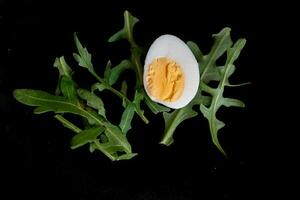 Easter card with egg on a black background and green leaves photo