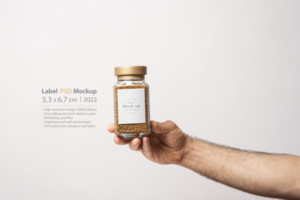 A male hand holding an instant coffee glass jar with blank label psd