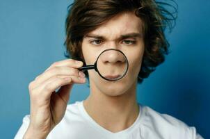 guy in a white t-shirt magnifying glass in his hands face problems photo