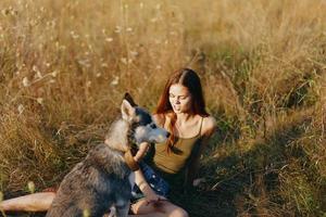 mujer sentado en campo con perro tejonero perro sonriente mientras gasto hora al aire libre con perro amigo foto