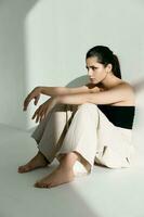 barefoot woman in fashionable clothes sitting on the floor photo