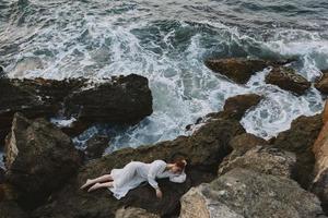 beautiful woman lying on rocky coast with cracks on rocky surface unaltered photo