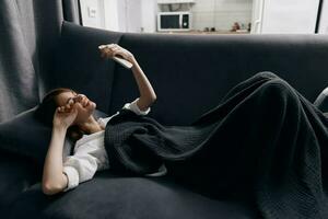a woman lies on a sofa in an apartment with a mobile phone in her hand photo