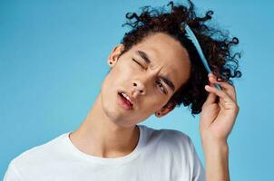 guy model with a comb in his hand and curly hair blue background portrait photo