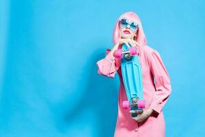 portrait of a woman with skateboard in pink wig blue background photo