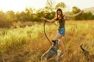 un mujer se ríe y obras de teatro con un perro en naturaleza en un campo sonriente abrazando un fornido perro foto