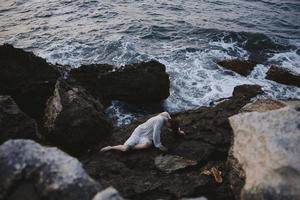 woman in a white dress lying on a stone in a white dress view from above photo