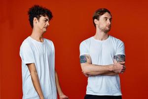 Two men in white t-shirts stand next to communication red background photo