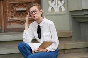 student with glasses walking around the city with a book education photo