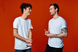 Two cheerful friends in white t-shirts stand side by side isolated background photo