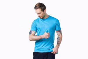 guy with dumbbells go in for sports in a blue t-shirt on a light background photo