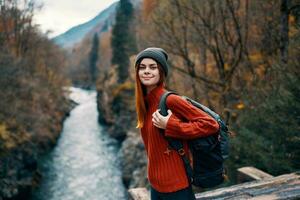 cheerful woman hiker in autumn clothes in the forest near the river photo