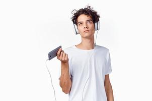 pelo rizado chico en auriculares con un teléfono en su manos música tecnología foto