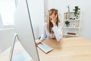 Upset blonde businesswoman made big mistake in report touch face makes facepalm sitting at workplace in modern office. Unhappy employee work on computer online in support service. Wide angle photo