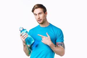 hombre en un azul camiseta con un botella de agua en su mano en un blanco antecedentes Copiar espacio foto