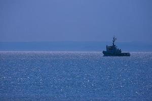 landscape a small ship sailing on the blue sea and cloudless sky photo