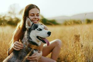 Woman and her husky dog happily stroll through the grass in the park smile with teeth fall sunset walk with pet, travel with a dog friend photo