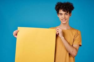 Cheerful man with curly hair yellow poster advertising blue background photo