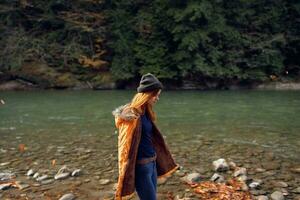 woman in a yellow jacket near the river admires nature Autumn forest photo