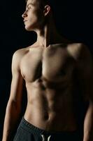 athlete with a naked torso looking to the side on a black background cropped view photo