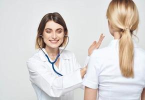 doctor woman in a medical gown with a stethoscope communicates with a patient back view photo