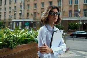 mujer gerente en blanco camisa al aire libre con documentos foto
