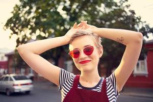 alegre mujer vistiendo Gafas de sol al aire libre posando estilo de vida foto