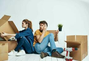 man and woman sitting on the floor with their backs to each other renovation work moving a flower in a pot photo