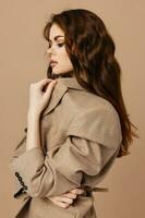 beautiful brunette cosmetics coat luxury side view beige background photo