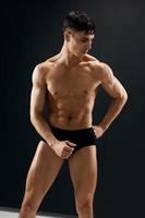 hombre con muscular cuerpo posando en oscuro bragas foto