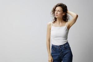 Upset unhappy frustrated curly woman in basic white t-shirt touches hair need professional psychological help posing isolated on over white background. People Emotions Lifestyle concept. Copy space photo