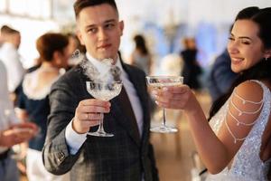 newlyweds at a banquet pour champagne into a pile of glasses photo