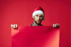 handsome man in a santa hat holding a banner holiday red background photo