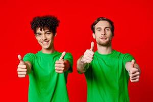 Cheerful friends in green t-shirts gesturing with hands emotions red background photo