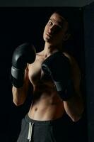 athlete in boxing gloves on black background portrait cropped view photo