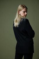 The blonde poses with her back to the camera. Concept photo for clothing brands. Cool offer for fashionable suits