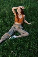 A woman lies on fresh spring green grass in a park without mosquitoes or ticks and enjoys relaxing while watching the sunset. The concept of safe outdoor recreation photo