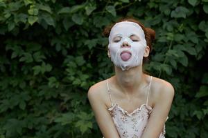 Nice woman Anti-wrinkle mask She leaned forward and sticks out her tongue bare shoulders photo