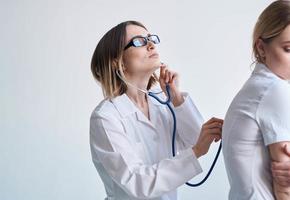 Professional doctor woman with stethoscope and female patient side view photo