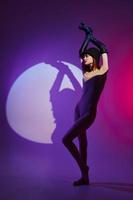 Pretty young female posing on stage spotlight silhouette disco color background unaltered photo