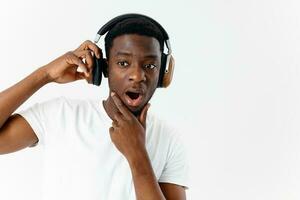 a man with a surprised expression in headphones listening to music light background photo