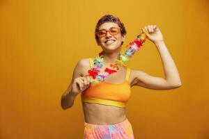 Woman with floral Hawaiian wreath around her neck has fun dancing and smiling in bright clothing against an orange background photo