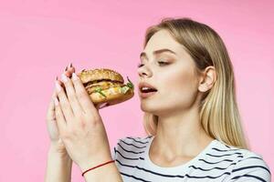 woman in striped t-shirt hamburger delicious sandwich snack pink background photo